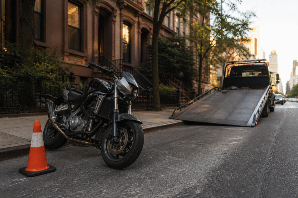 A disabled motorcycle safely beside a towing ramp on a New York City street
