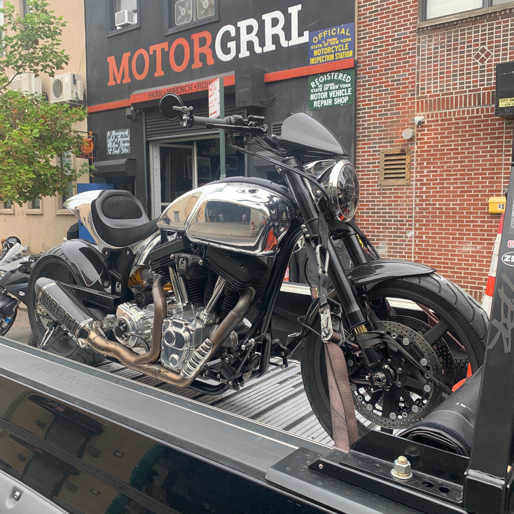 Black touring motorcycle secured outside a motorcycle shop