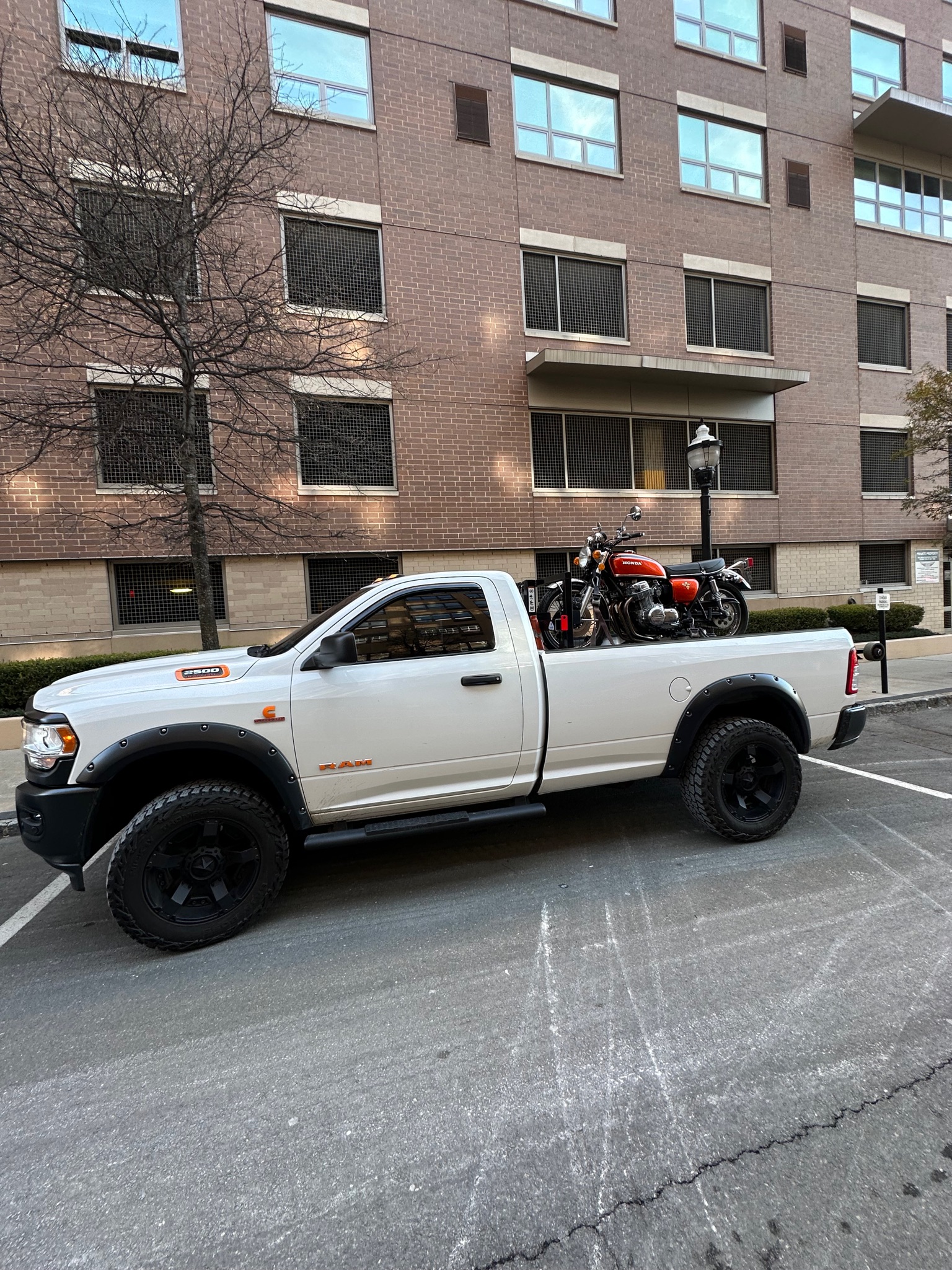 MAD Transpo NYC white pickup with a motorcycle secured for transport